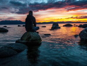 Man sitting on rock in water